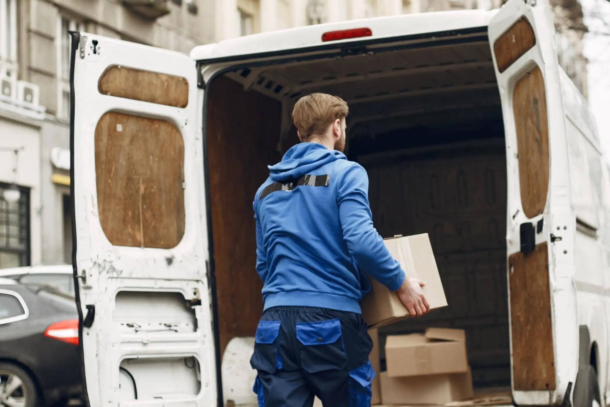 Ein beladener Transporter steht mit offenen Türen am Straßenrand.
